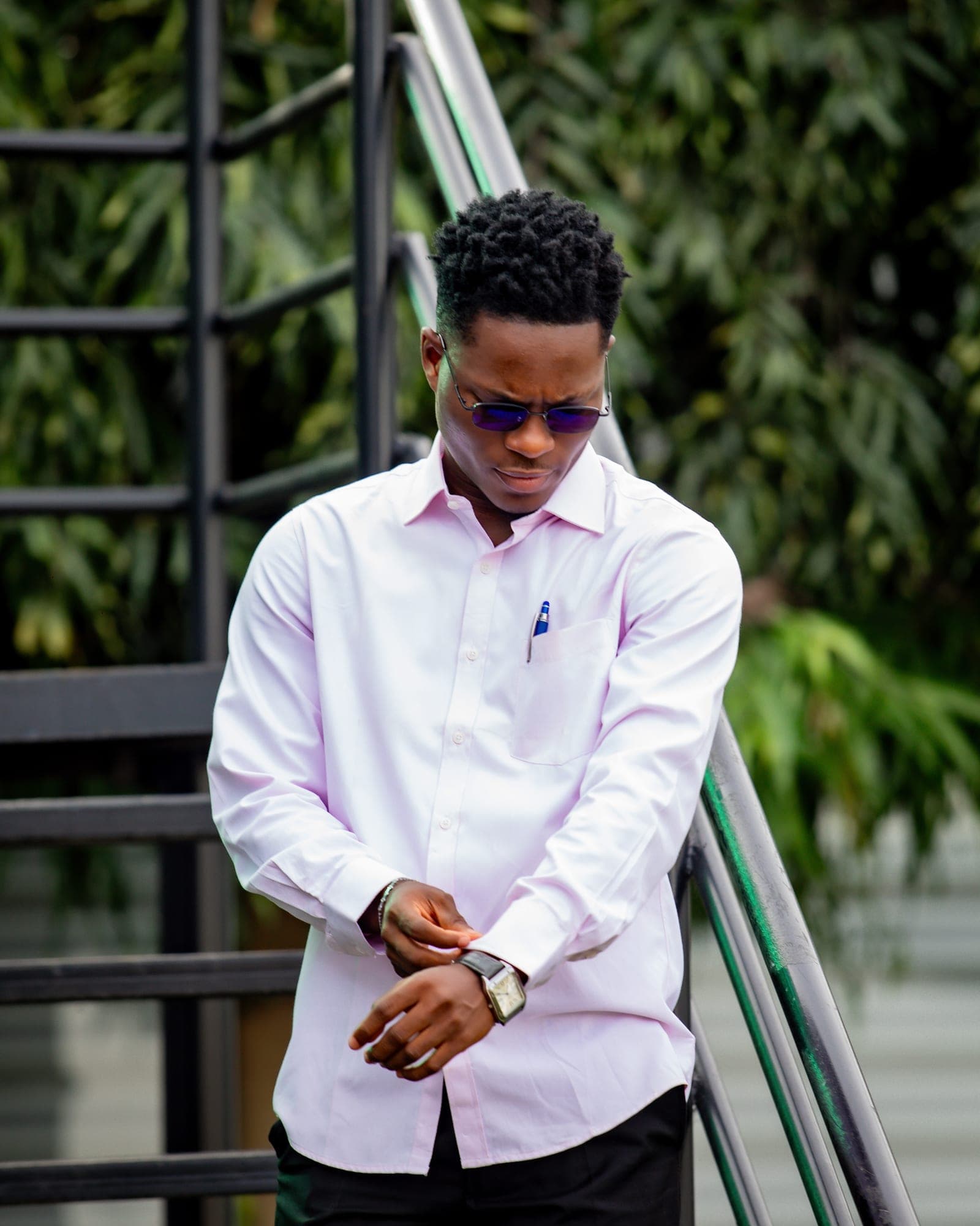 Obed Afram on an outdoor staircase, checking his watch